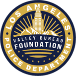 The image is a circular logo of the Los Angeles Police Department Valley Bureau Foundation, featuring a building with rays and mountains in the background.